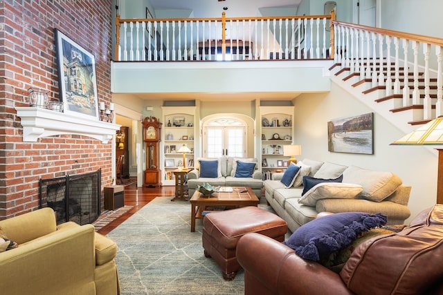 living room featuring a fireplace, stairs, a high ceiling, and wood finished floors