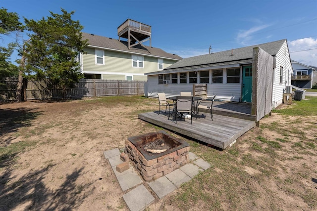 rear view of property featuring an outdoor fire pit, outdoor dining area, fence, a lawn, and a wooden deck