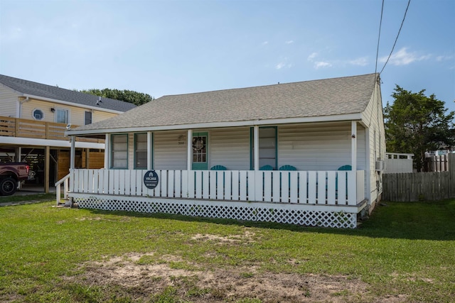 rear view of property featuring covered porch, a yard, and a shingled roof