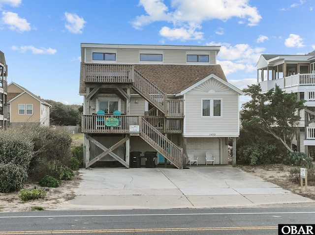 1400 N Virginia Dare Trl, Kill Devil Hills, NC 27948 - beach home with stairway, a shingled roof, an attached garage, and concrete driveway
