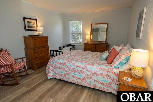 bedroom with wood finished floors and ornamental molding