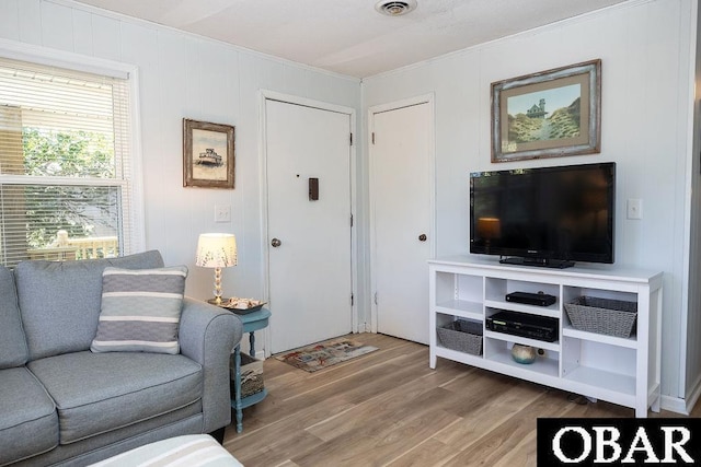 living room featuring crown molding, wood finished floors, and visible vents