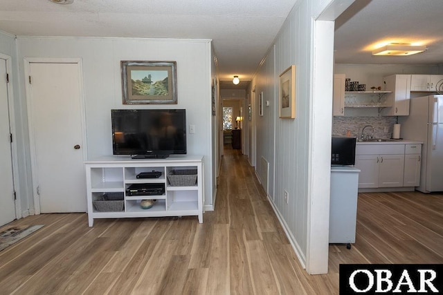 unfurnished living room with light wood finished floors, visible vents, crown molding, and a sink