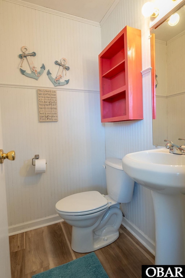 half bathroom with baseboards, toilet, and wood finished floors