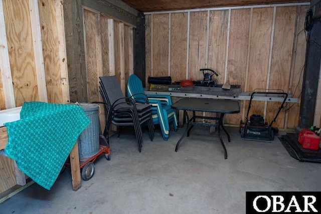 miscellaneous room featuring unfinished concrete flooring and wooden walls