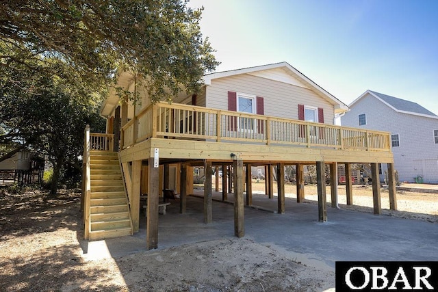 back of house with a wooden deck, driveway, a carport, and stairs