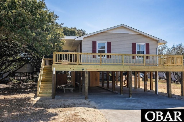 rear view of property featuring a carport, driveway, a wooden deck, and stairs