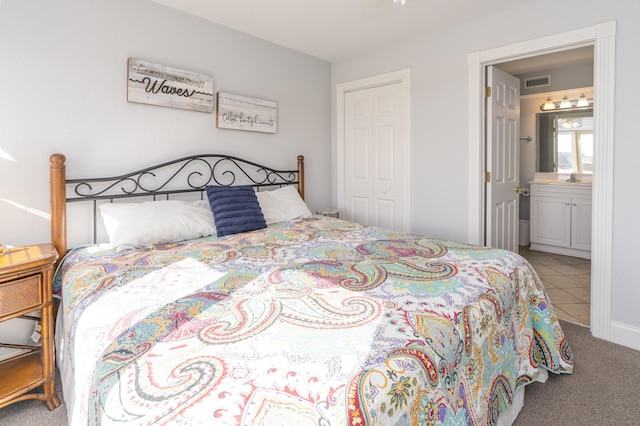 carpeted bedroom with a sink, visible vents, ensuite bathroom, and tile patterned flooring