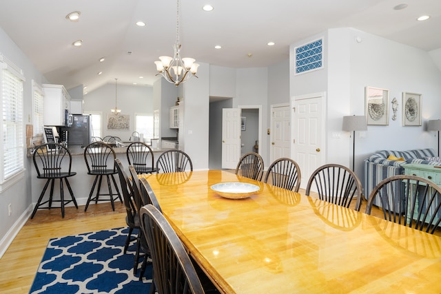 dining space featuring light wood-style flooring, a notable chandelier, recessed lighting, and high vaulted ceiling