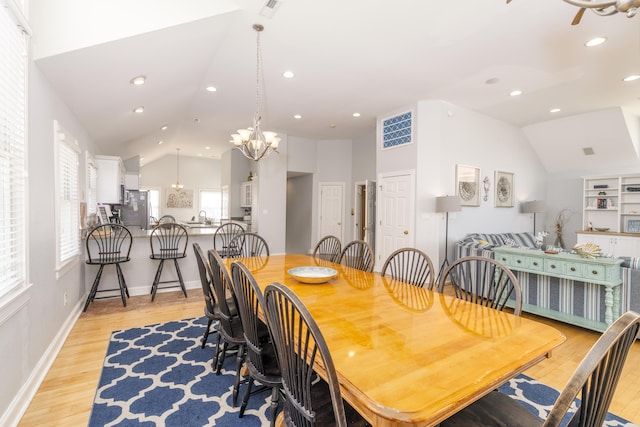 dining space featuring recessed lighting, a notable chandelier, light wood-style floors, and vaulted ceiling