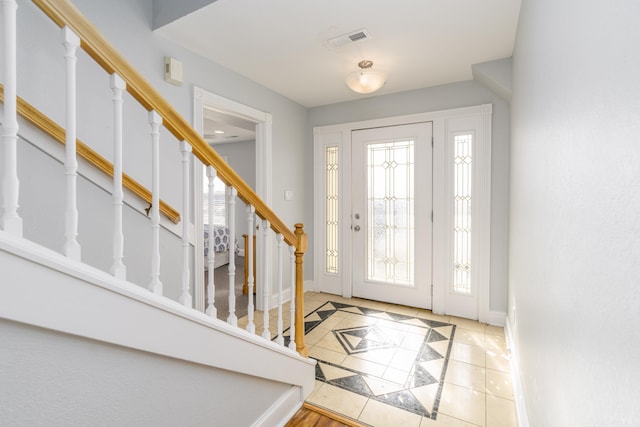 entrance foyer with tile patterned floors, visible vents, baseboards, and stairs