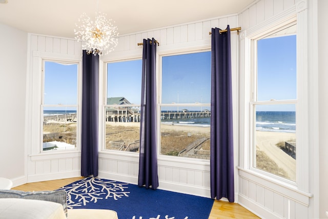 bedroom with wood finished floors, an inviting chandelier, and a water view