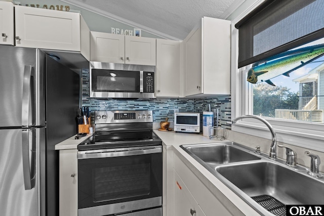 kitchen with stainless steel appliances, lofted ceiling, light countertops, white cabinets, and a sink