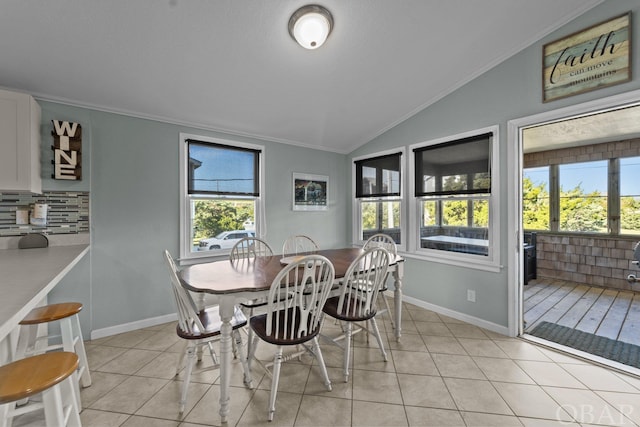 dining space with light tile patterned floors, baseboards, vaulted ceiling, and crown molding