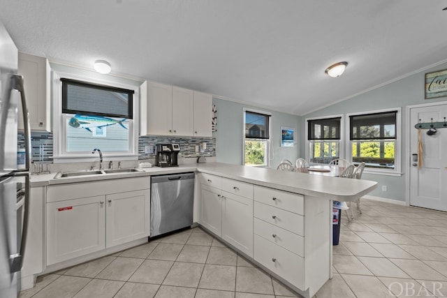 kitchen featuring light countertops, appliances with stainless steel finishes, white cabinetry, a sink, and a peninsula