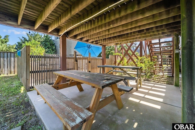 view of patio featuring outdoor dining space, stairway, and a fenced backyard