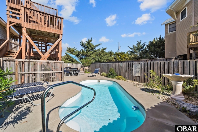 community pool featuring a patio area, a fenced backyard, stairs, and a deck