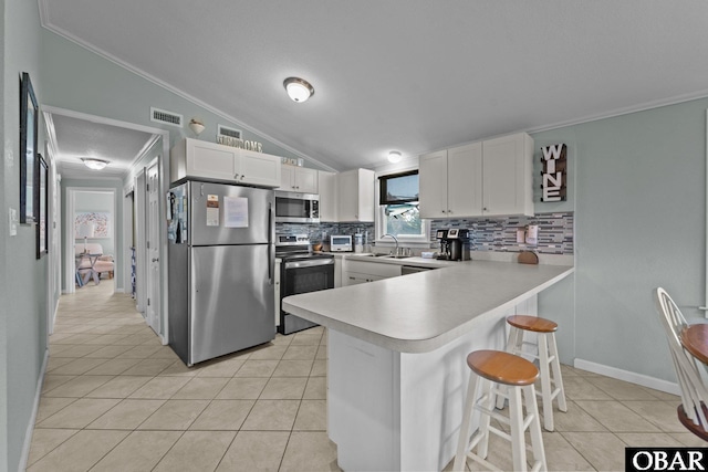 kitchen featuring light countertops, visible vents, appliances with stainless steel finishes, white cabinets, and a peninsula