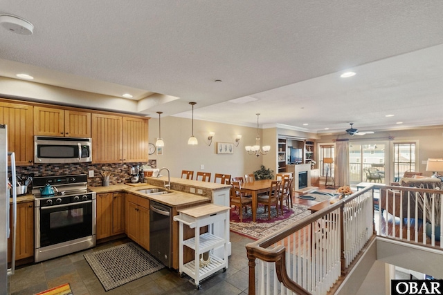 kitchen with a peninsula, a sink, open floor plan, appliances with stainless steel finishes, and decorative backsplash