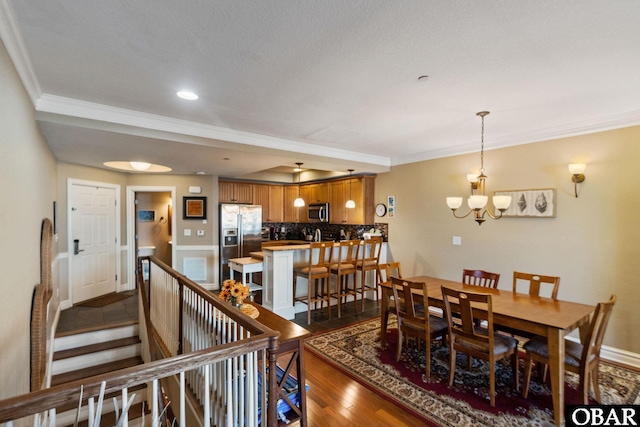 dining space with dark wood-style floors, a notable chandelier, baseboards, and crown molding