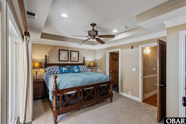 bedroom with a tray ceiling, carpet flooring, visible vents, and baseboards