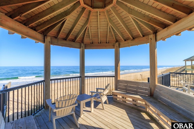 wooden terrace with a water view, a beach view, and a gazebo