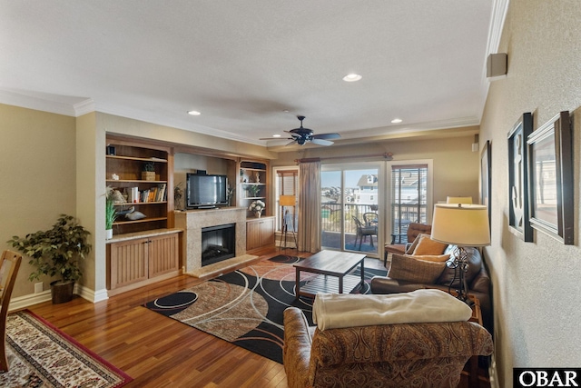 living area with crown molding, a fireplace, baseboards, and wood finished floors