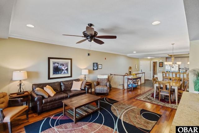 living room featuring hardwood / wood-style flooring, ceiling fan with notable chandelier, crown molding, and recessed lighting