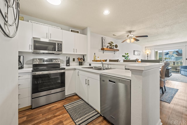 kitchen featuring light countertops, appliances with stainless steel finishes, white cabinetry, a sink, and a peninsula