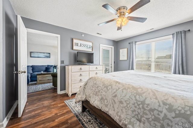 bedroom featuring dark wood-style flooring, visible vents, a ceiling fan, a textured ceiling, and baseboards