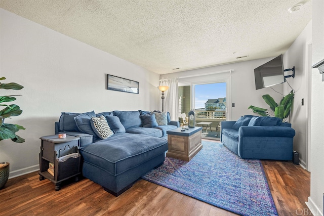 living room with dark wood-type flooring, a textured ceiling, and baseboards