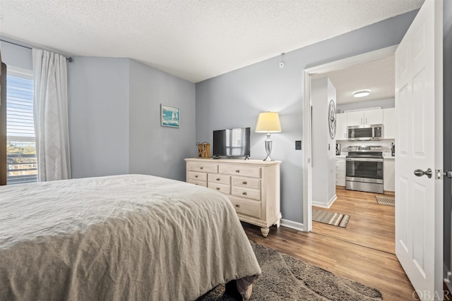 bedroom featuring a textured ceiling, wood finished floors, and baseboards