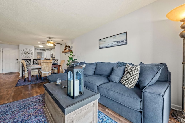 living area featuring dark wood finished floors, a textured ceiling, and ceiling fan