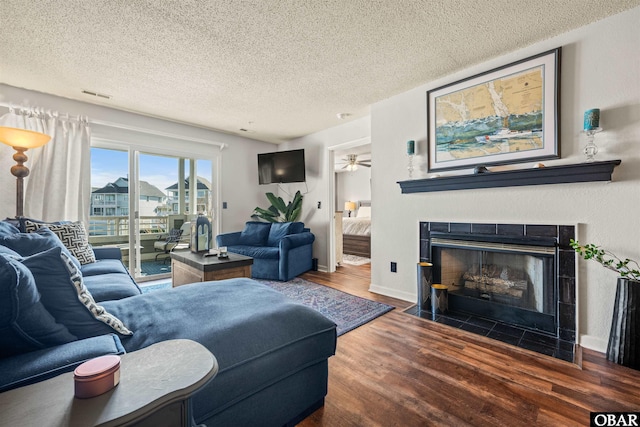 living room with visible vents, dark wood-type flooring, a fireplace with flush hearth, a textured ceiling, and baseboards