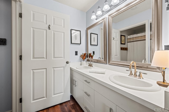 bathroom featuring double vanity, a shower with curtain, a sink, and wood finished floors