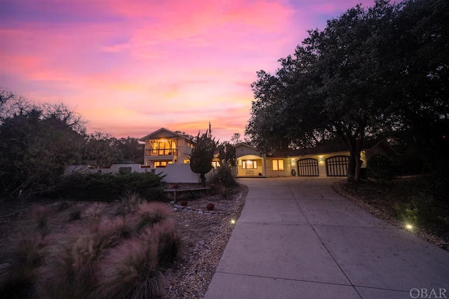 view of front of property with driveway, a balcony, a gate, and stucco siding