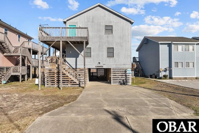 view of front of home featuring a carport, concrete driveway, and stairs