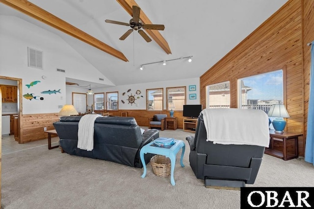 living room with wood walls, visible vents, beamed ceiling, and light colored carpet