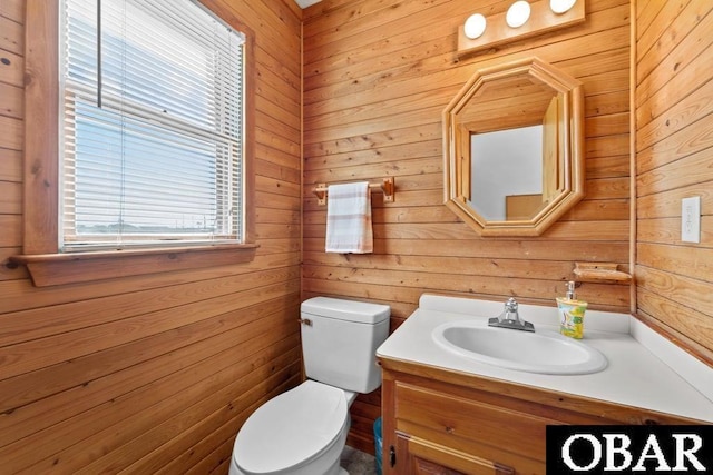 half bath featuring wooden walls, vanity, and toilet