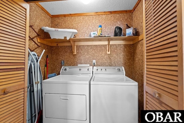 laundry area featuring ornamental molding, laundry area, a textured ceiling, and washing machine and clothes dryer