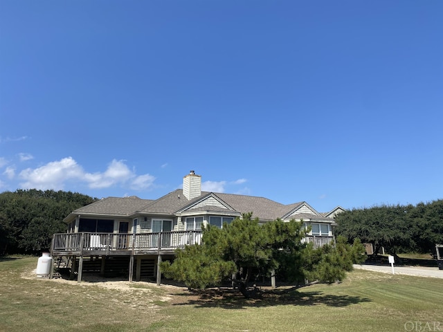 rear view of house featuring a yard, a chimney, and a wooden deck