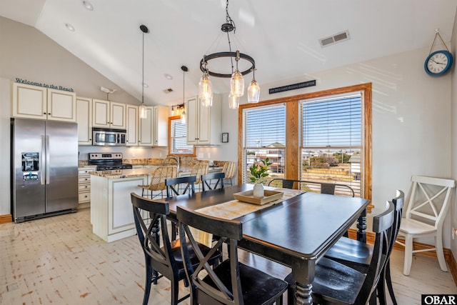 dining space with vaulted ceiling, light wood-style flooring, and visible vents