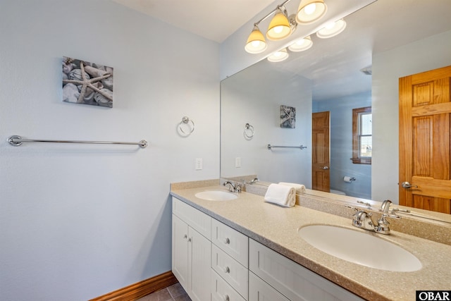 full bathroom with double vanity, a sink, and baseboards