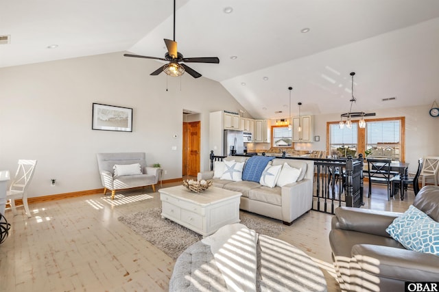 living area with visible vents, baseboards, ceiling fan, light wood-style floors, and high vaulted ceiling