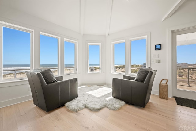 sunroom featuring a water view, a view of the beach, a wealth of natural light, and lofted ceiling