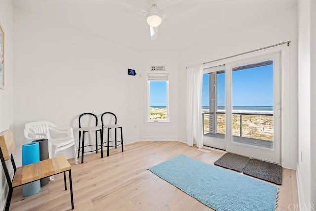 sitting room featuring baseboards, a water view, and light wood-style floors