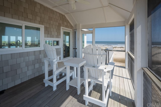 wooden terrace featuring a ceiling fan, a water view, and a beach view