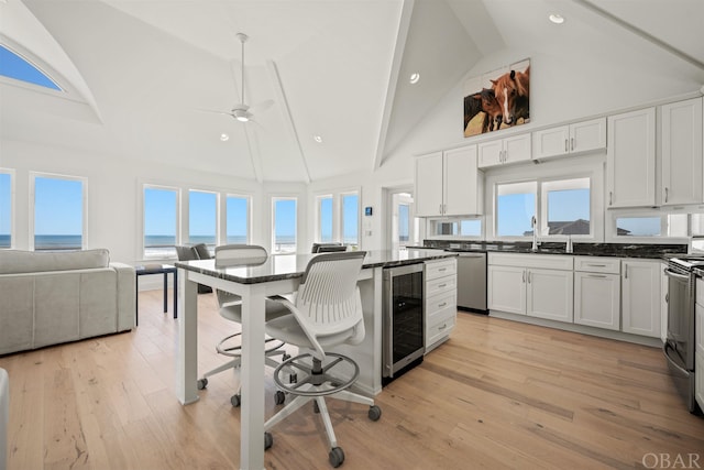 kitchen featuring open floor plan, stainless steel appliances, wine cooler, and white cabinets