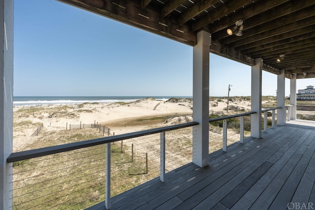 wooden deck featuring a water view and a view of the beach