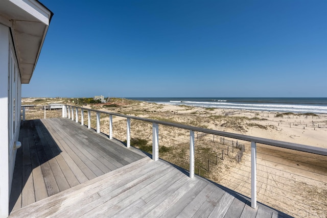 wooden deck featuring a water view and a beach view